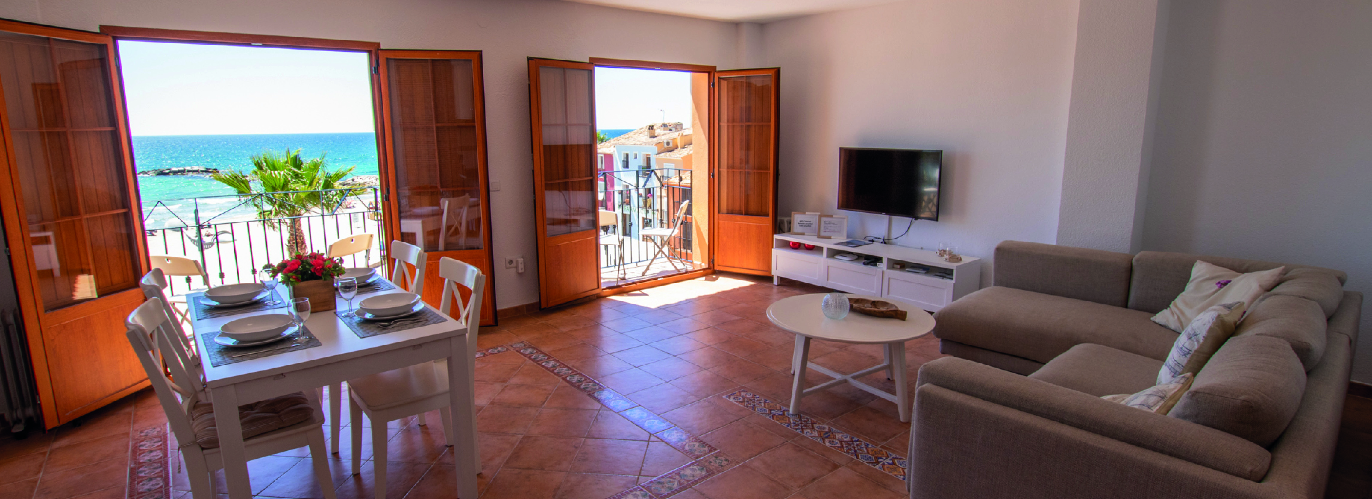 Stor og lys stue med to doble dører som kan åpnes til balkonger som vender mot stranden